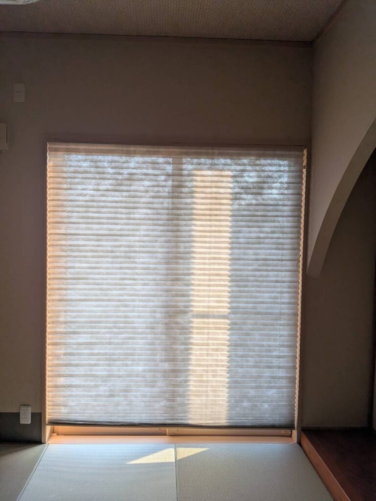 施工前の和室。和紙調の単色プリーツスクリーンが設置された窓辺の写真。