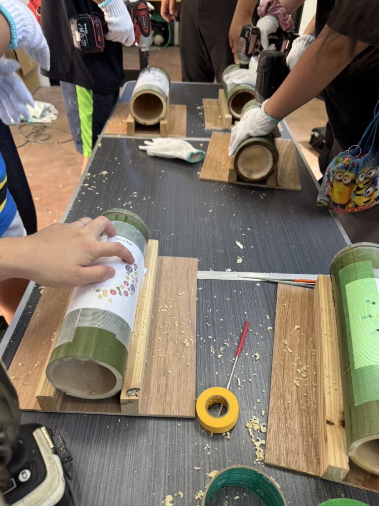 竹灯籠づくりワークショップで、子供たちが竹にドリルで穴あけ作業をしているDIYの様子